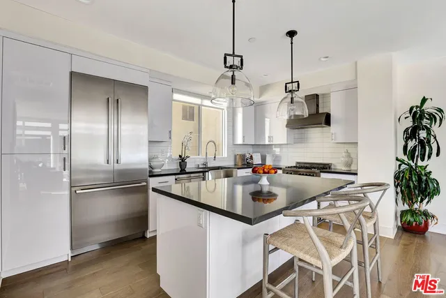 a kitchen with stainless steel appliances a sink a stove a refrigerator and center island