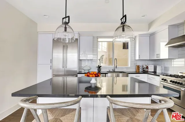 a kitchen with stainless steel appliances granite countertop a stove a sink dishwasher a dining table and chairs with wooden floor