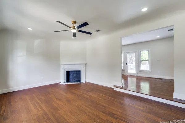 a view of empty room with wooden floor and fan