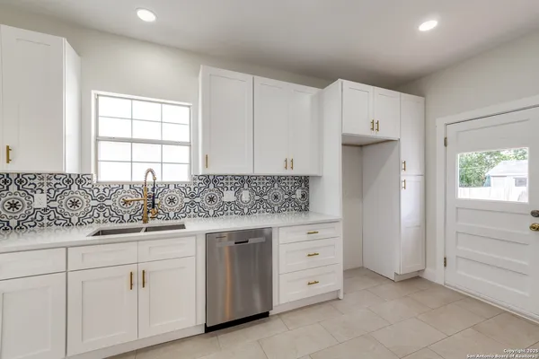 a kitchen with granite countertop white cabinets and sink