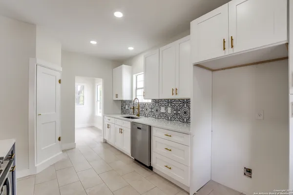 a kitchen with white cabinets and sink