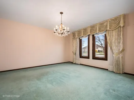 a view of an empty room with window and chandelier fan