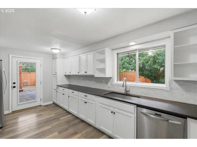 a kitchen with granite countertop white cabinets and window