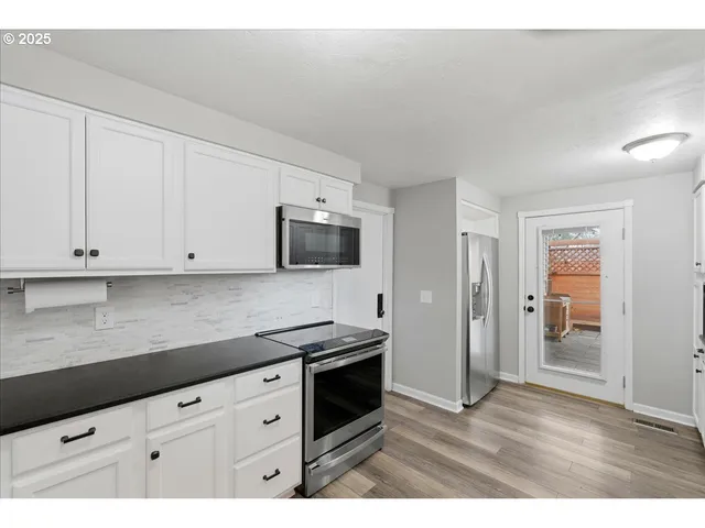 a kitchen with stainless steel appliances a stove a microwave and white cabinets