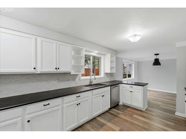 a kitchen with stainless steel appliances granite countertop a sink and cabinets with wooden floor