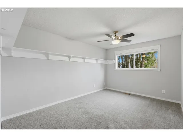 a view of an empty room with a ceiling fan and a window