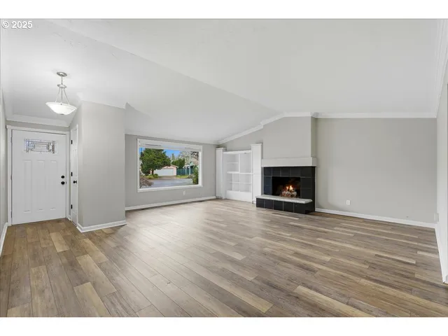 a view of empty room with wooden floor and fireplace