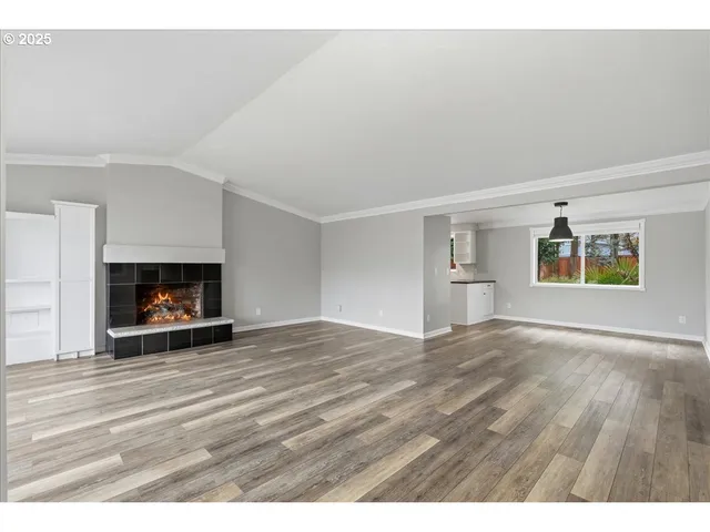a view of empty room with wooden floor and fireplace