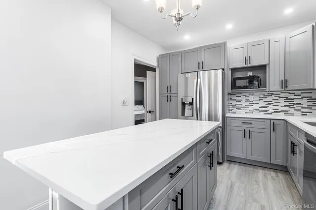 a kitchen with kitchen island a sink stainless steel appliances and refrigerator