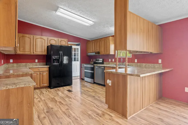 a kitchen with stainless steel appliances kitchen island granite countertop a refrigerator a stove top oven and a sink with wooden floor