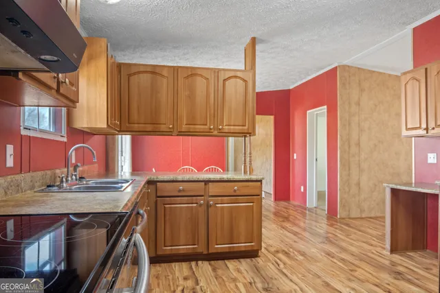 a view of a kitchen with stainless steel appliances granite countertop a stove and wooden cabinets