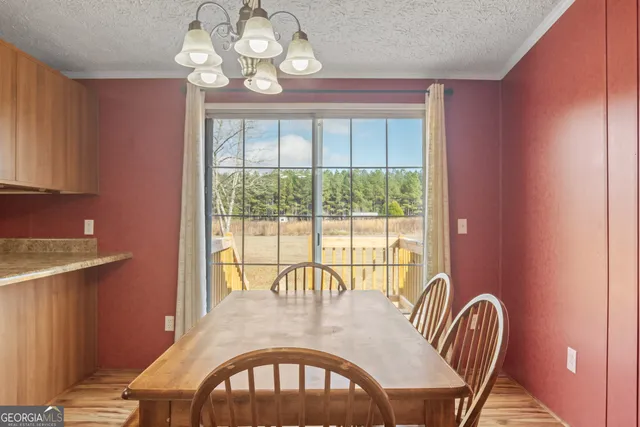 a view of a dining room with furniture a chandelier and a window