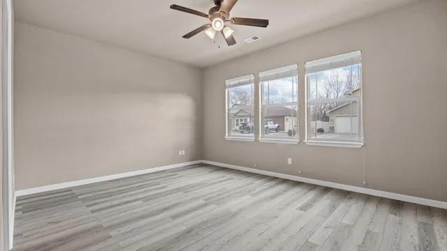 a view of an empty room with wooden floor and a window