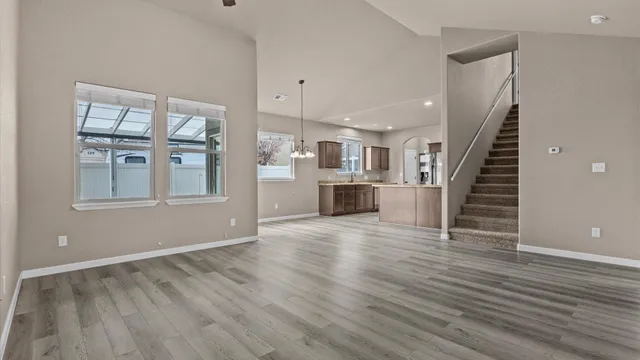 a view of empty room with wooden floor and kitchen view