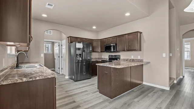 a kitchen with stainless steel appliances granite countertop a sink stove and refrigerator