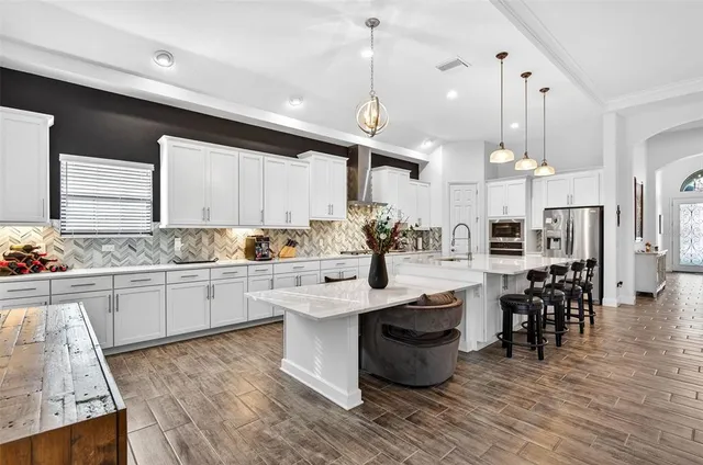 a large white kitchen with lots of counter space and stainless steel appliances
