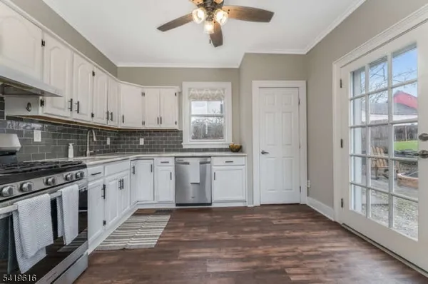 a kitchen with granite countertop a stove a sink and a refrigerator with white cabinets