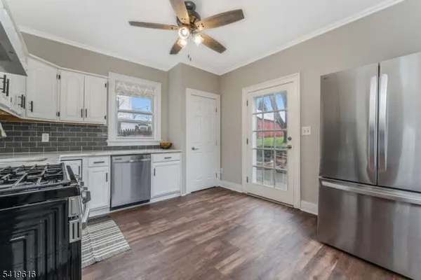 a kitchen with granite countertop a refrigerator a stove a sink and white cabinets with wooden floor