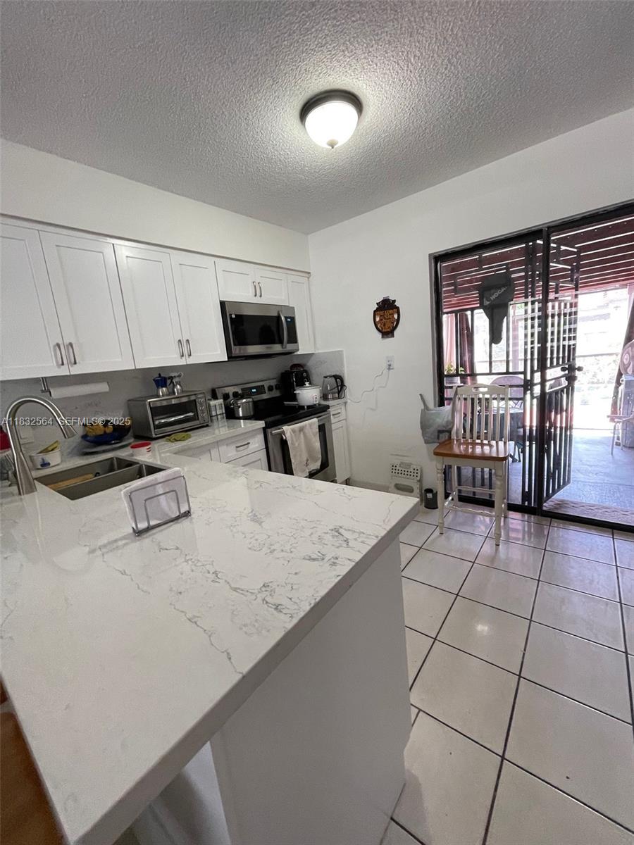 12057 Southwest 10th Street, Unit 202 Miami, FL 33184 - Photo 3 of 12 a kitchen with stainless steel appliances a stove a sink a microwave and a refrigerator