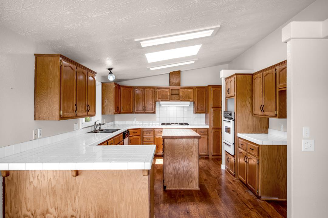 10721 Shenandoah Road Plymouth, CA 95669 - Photo 19 of 48 a kitchen with a stove a refrigerator a sink dishwasher and wooden cabinets with wooden floor