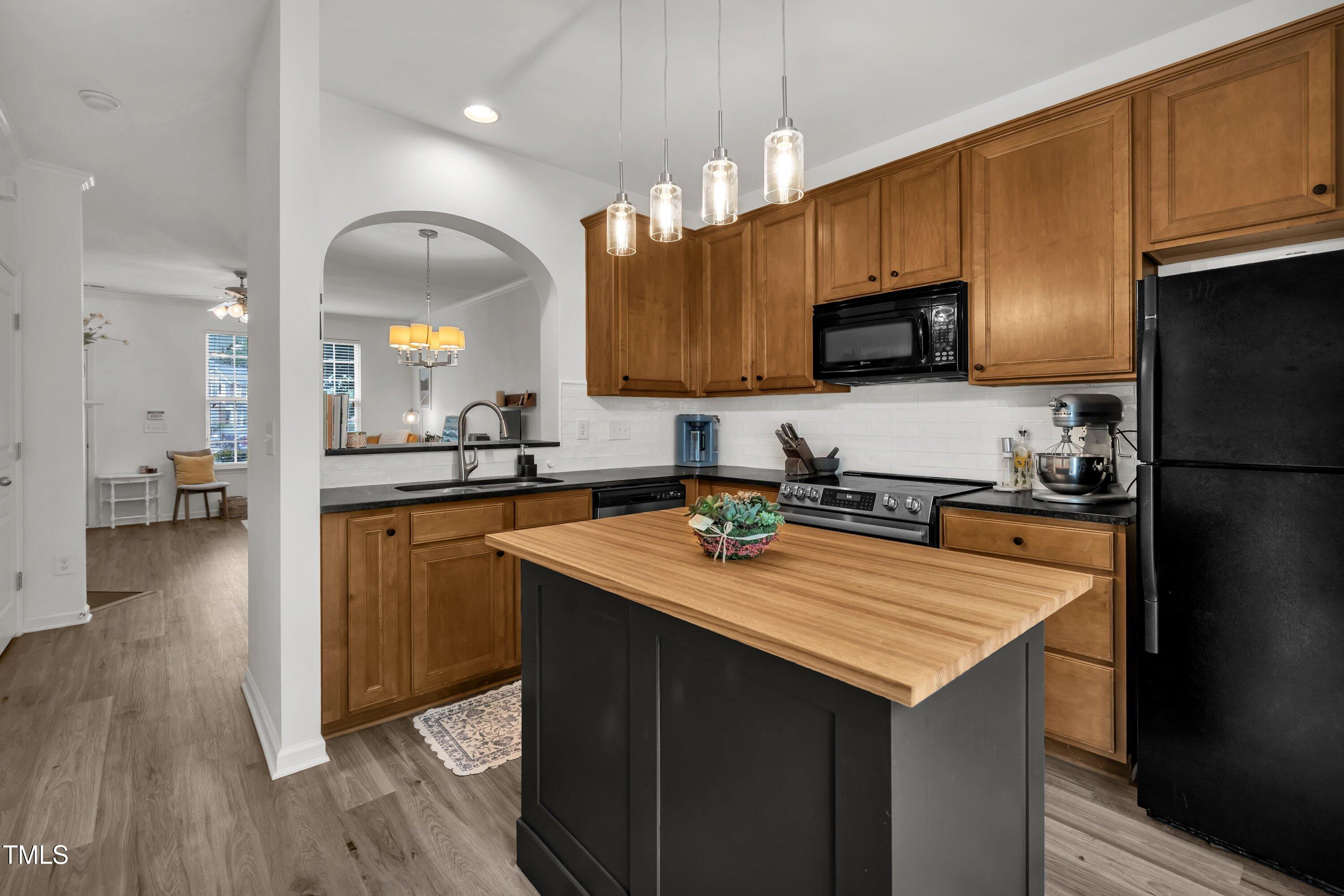 3583 Sugar Tree Place Durham, NC 27713 - Photo 15 of 50 a kitchen with a sink a kitchen island a stove a microwave and cabinets