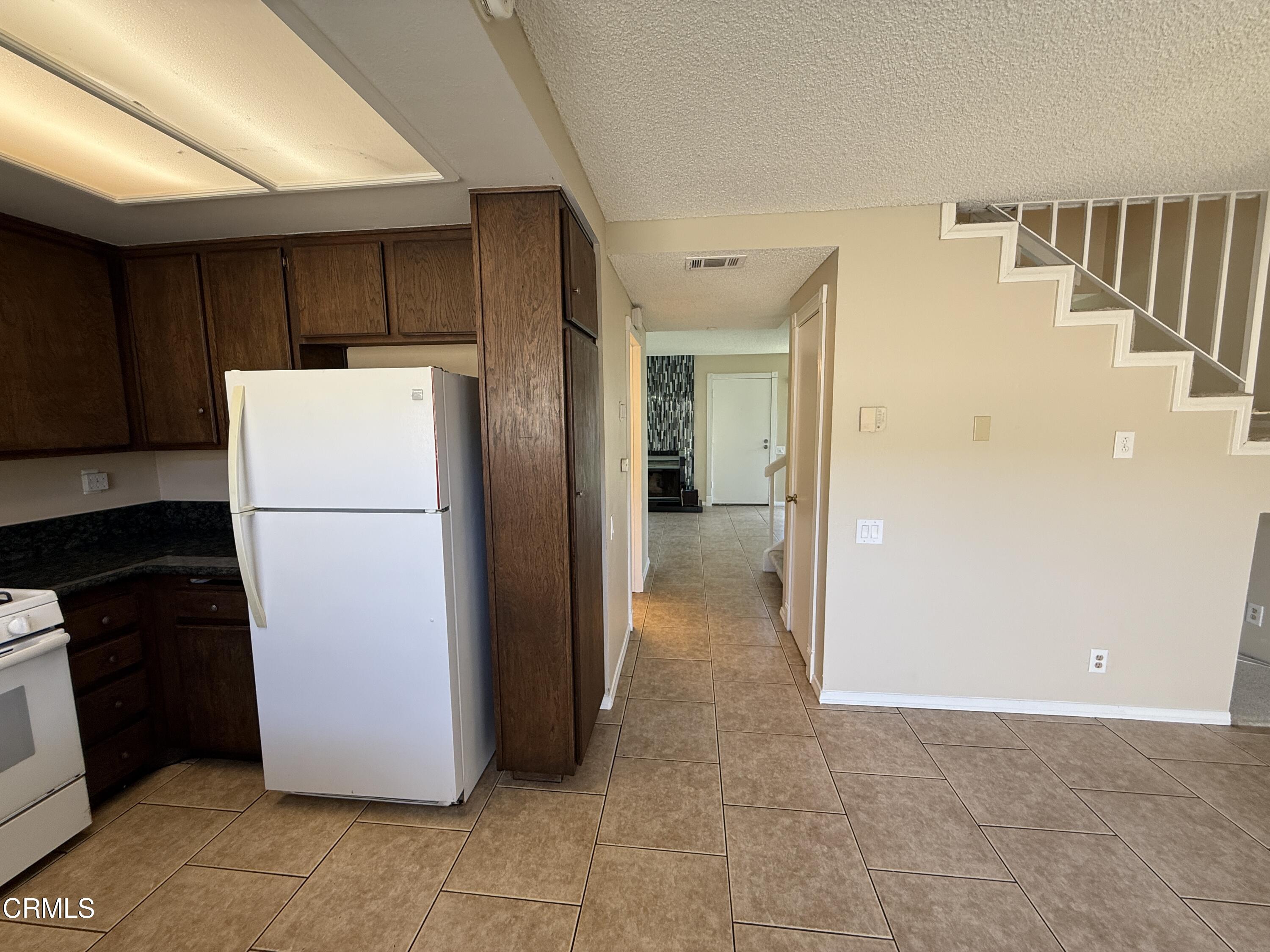 5209 Perkins Road Oxnard, CA 93033 - Photo 12 of 28 a view of a kitchen with refrigerator and white cabinets