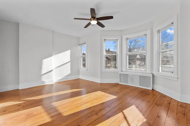 a view of empty room with wooden floor and fan