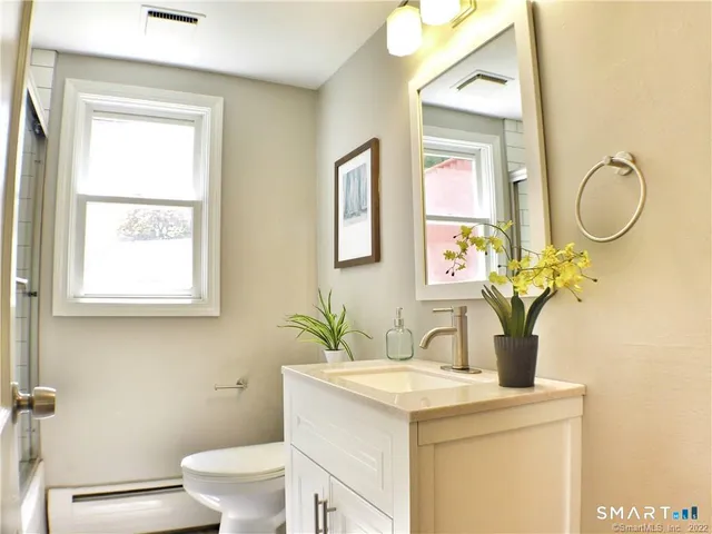 a bathroom with a granite countertop toilet sink and mirror
