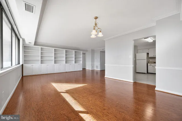 a view of an empty room with wooden floor and windows