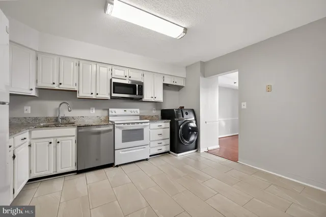 a kitchen with cabinets stainless steel appliances and sink