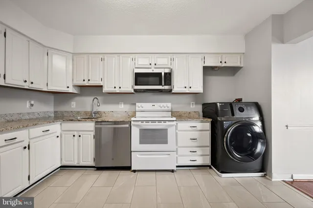 a kitchen with white cabinets and stainless steel appliances