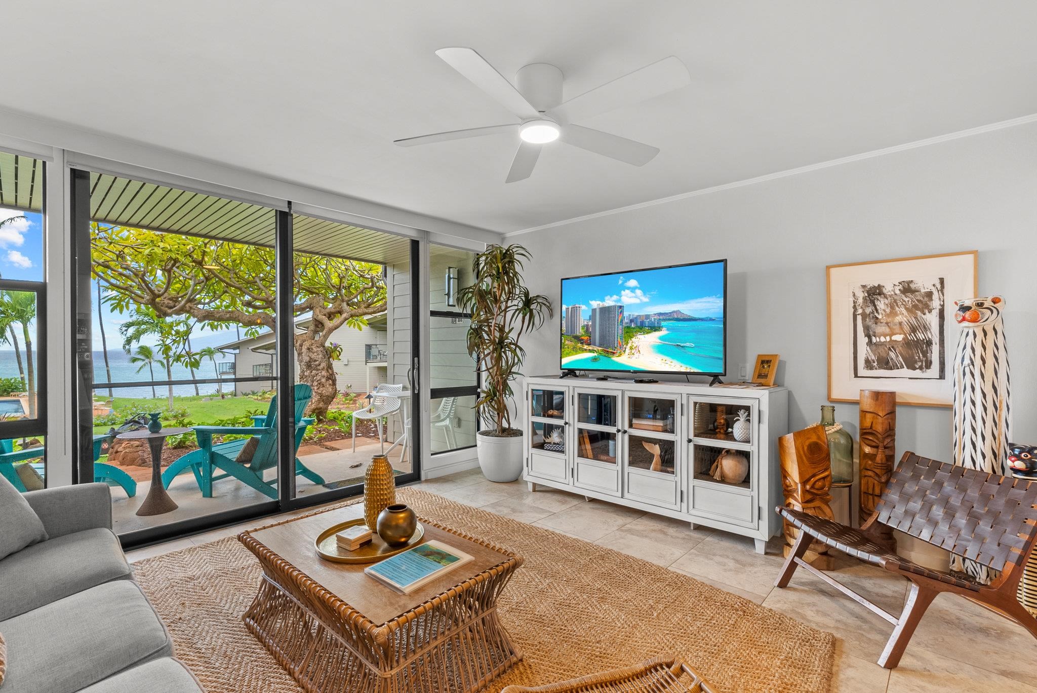 4057 Lower Honoapiilani Road, Unit 114 Lahaina, HI 96761 - Photo 3 of 23 a living room with furniture a flat screen tv and a floor to ceiling window