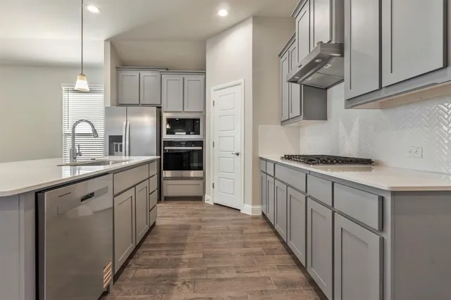 a kitchen with stainless steel appliances a sink stove refrigerator and cabinets