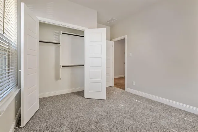 an empty room with closet and windows