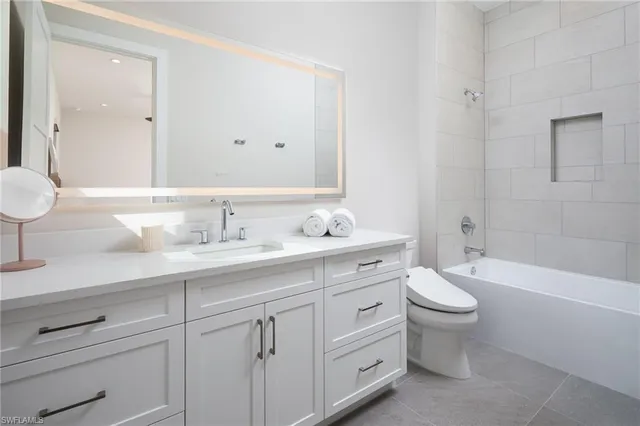 a bathroom with a double vanity sink a toilet and a bathtub