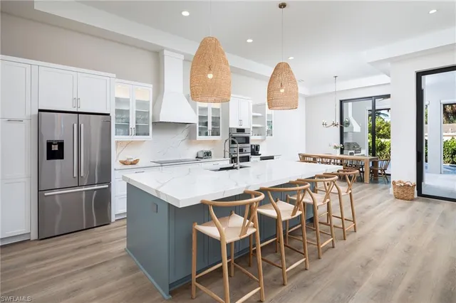 a kitchen with stainless steel appliances granite countertop a table chairs and a refrigerator