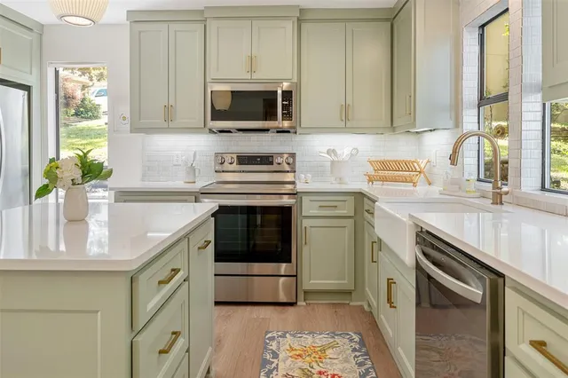 a kitchen with stainless steel appliances granite countertop a sink a stove a microwave a refrigerator and cabinets