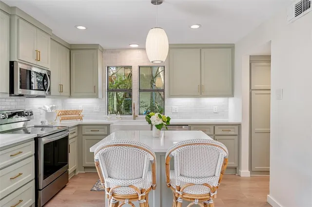 a kitchen with stainless steel appliances granite countertop a stove a sink a microwave a refrigerator and cabinets