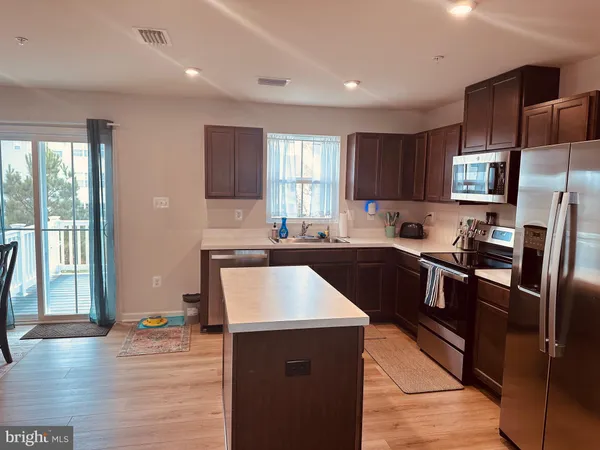 a kitchen with stainless steel appliances granite countertop a refrigerator a sink a stove a microwave and wooden cabinets
