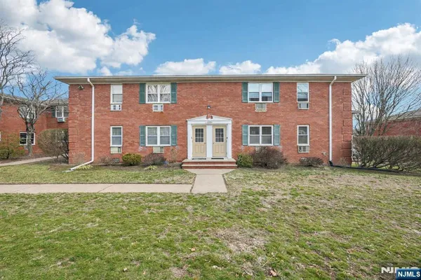 a view of a brick house next to a yard with big trees