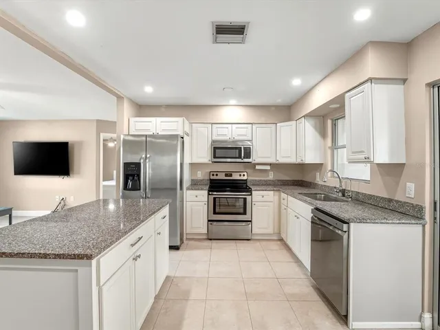 a large kitchen with granite countertop a large counter top stainless steel appliances and cabinets