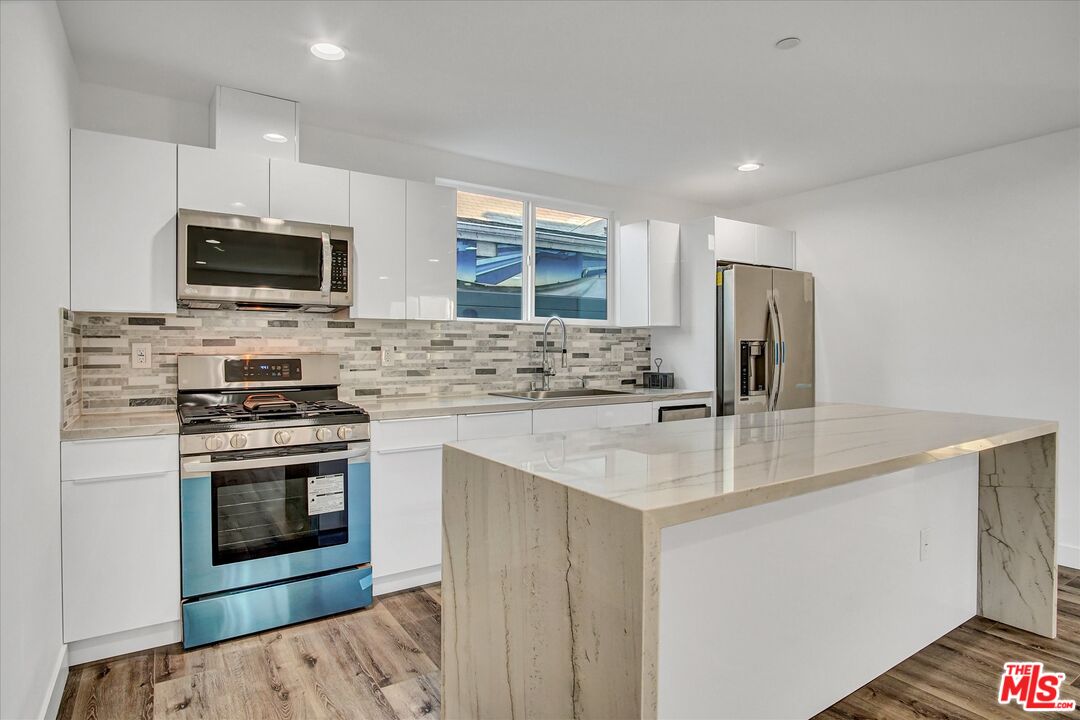 2419 South Cochran Avenue Los Angeles, CA 90016 - Photo 11 of 74 a kitchen with stainless steel appliances granite countertop a stove top oven a sink and a refrigerator