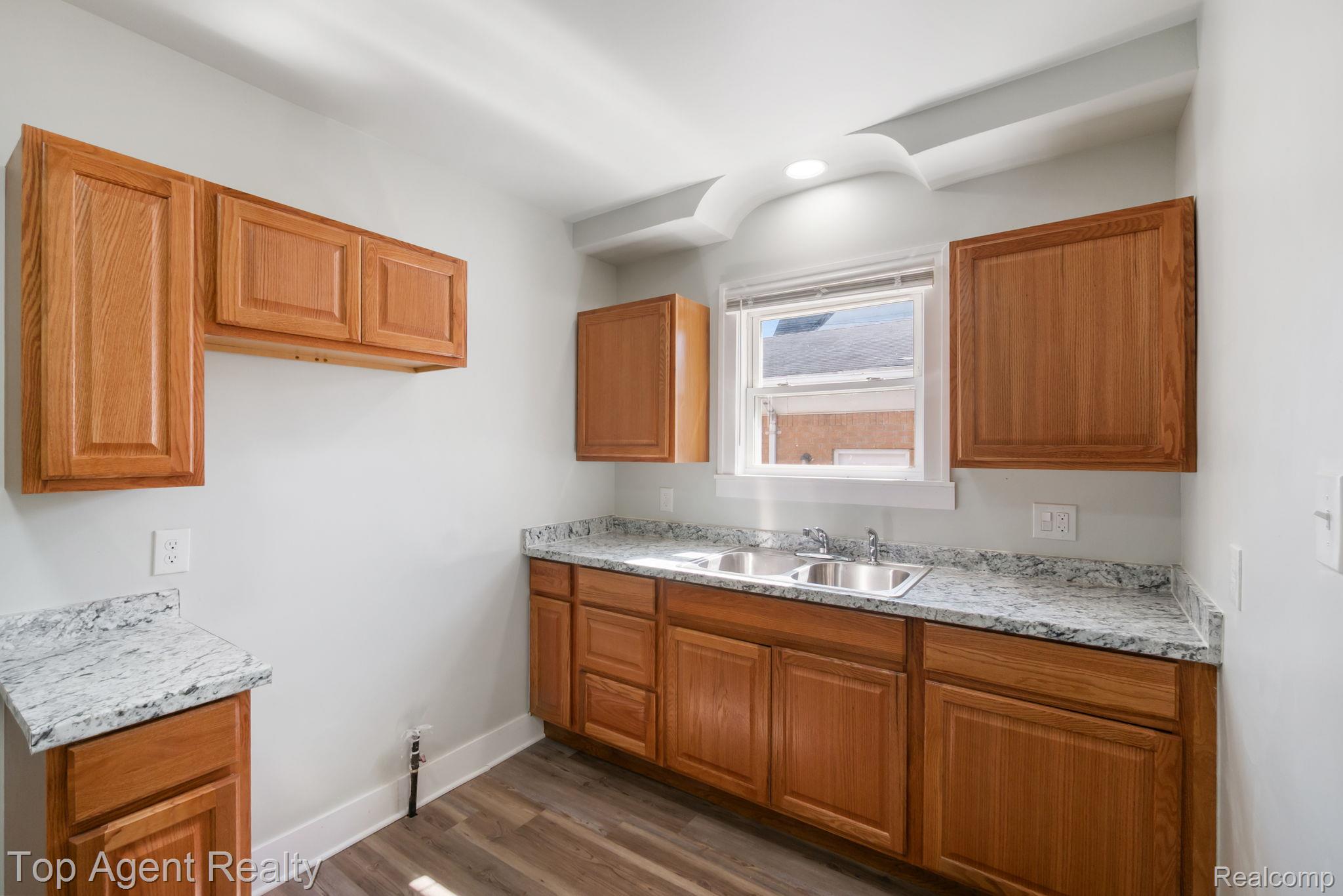 19217 Reno Street Detroit, MI 48205 - Photo 12 of 45 Kitchen featuring wood-finish cabinetry, light-toned countertops, and dual stainless steel sinks