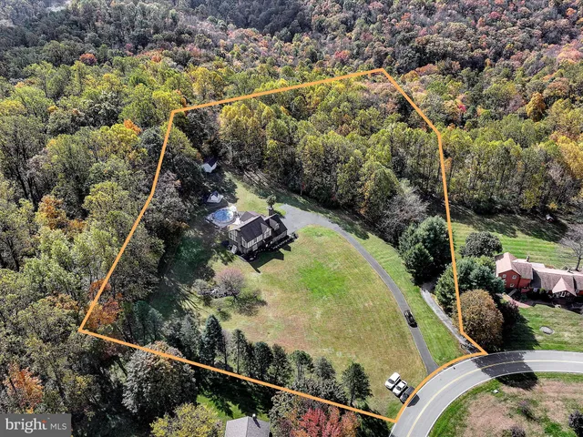 a view of a swimming pool with lawn chairs and a dining table under an umbrella