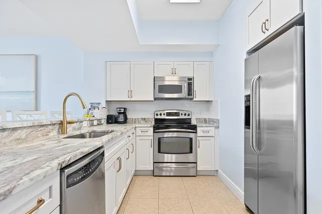a kitchen with stainless steel appliances granite countertop white cabinets a stove a microwave and a sink