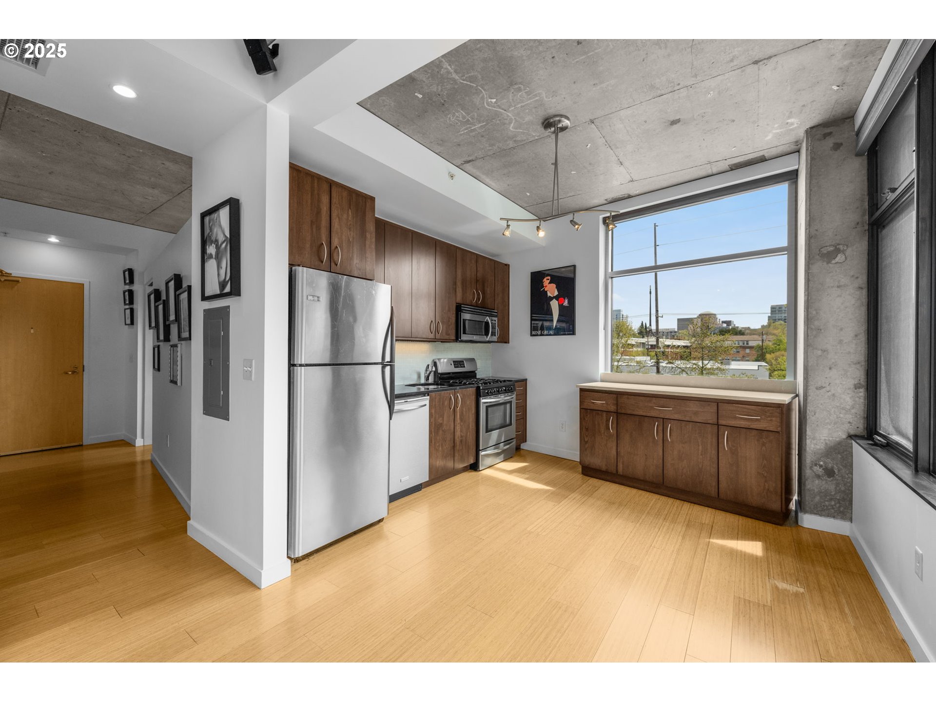 1234 Southwest 18th Avenue, Unit 305 Portland, OR 97205 - Photo 9 of 31 a kitchen with stainless steel appliances kitchen island granite countertop a refrigerator a stove a sink with a dining table and chairs