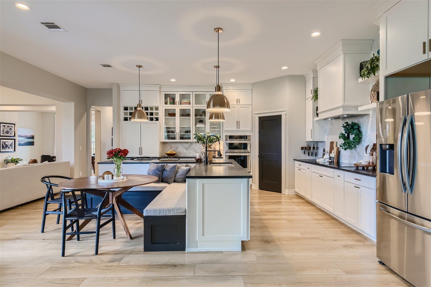 113 Vista View Trail Spicewood, TX 78669 - Photo 11 of 30 a kitchen with stainless steel appliances kitchen island granite countertop a table chairs and a refrigerator