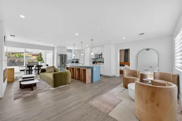 a living room with furniture kitchen view and large windows