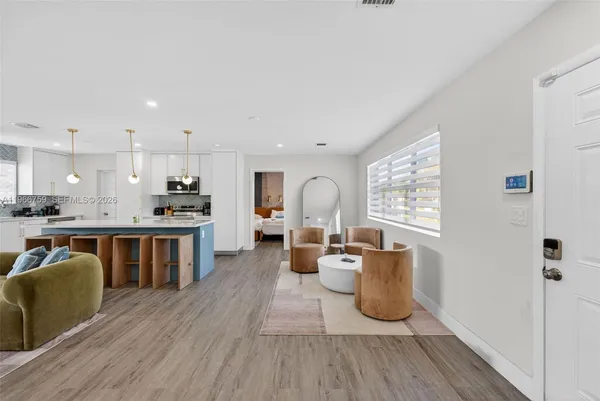 a open kitchen with stainless steel appliances granite countertop a stove a sink dishwasher and a refrigerator with wooden floor