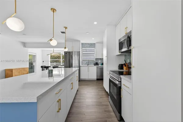 a large kitchen with kitchen island a large counter space a sink a stove and a refrigerator